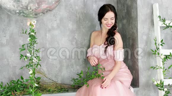 迷人的年轻女士穿着粉红色的裙子在春天的摄影会上摆着鲜花视频的预览图