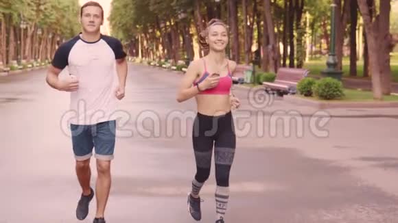 美丽的年轻女孩和男人在公园里训练跑步慢动作视频的预览图