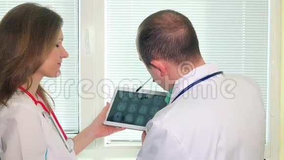 男性和女性医生分析平板电脑上的mrt头像视频的预览图