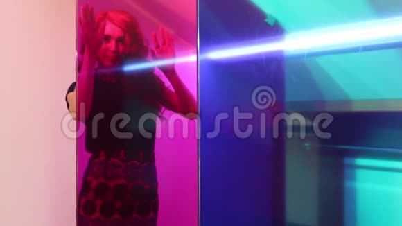 一位年轻的美女在房间的粉色玻璃后面摆姿势视频的预览图