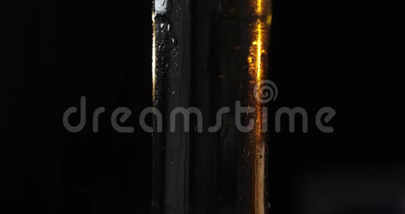 一瓶黑色背景的冷啤酒它慢慢地旋转凝结物视频的预览图