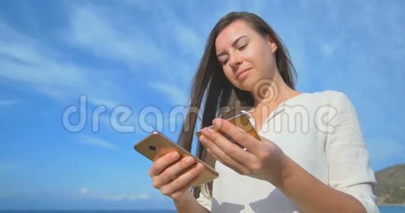 女人在度假时使用信用卡用手机上网购物蓝蓝大海背景清澈视频的预览图