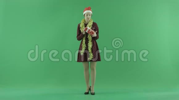 一位年轻女子正在寻找一份圣诞礼物并把它扔到绿色的屏幕上视频的预览图