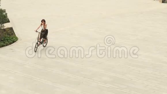 夏天骑自行车的妇女骑在广场上铺好的马路上视频的预览图