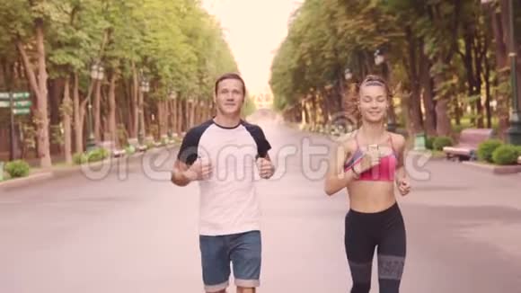 美丽的年轻女孩和男人在公园里训练跑步慢动作视频的预览图