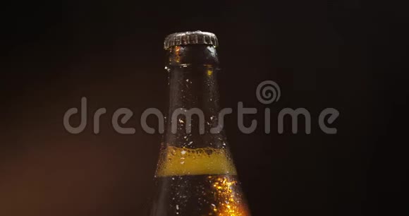 一瓶黑色背景的冷啤酒它慢慢地旋转凝结物视频的预览图