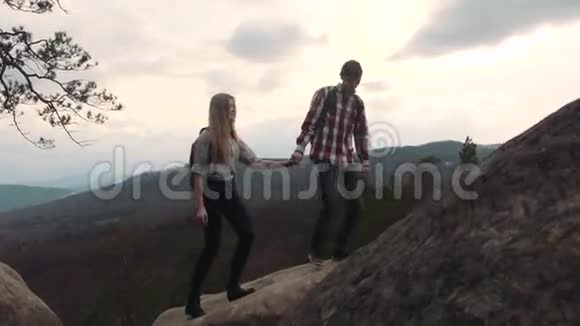 时髦的年轻夫妇走在山顶上牵手快乐的时刻年轻的恋人户外活动视频的预览图