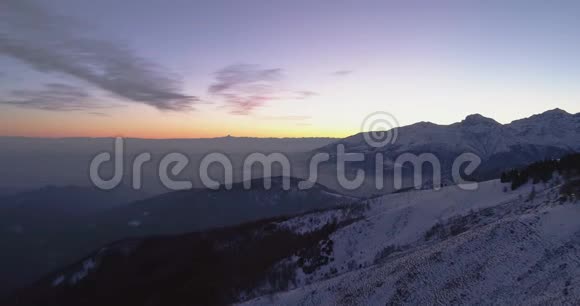 从空中俯瞰冬天的雪山汽车在路上行驶蓝色的黄昏或黎明的阿尔卑斯山视频的预览图