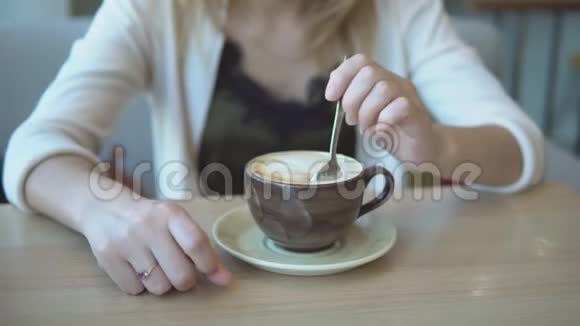 女孩手在一杯拿铁里搅拌糖视频的预览图