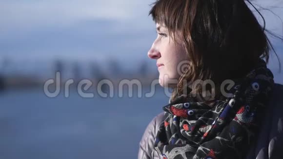 一位年轻可爱的微笑女人在冬季河流背景上的肖像视频的预览图