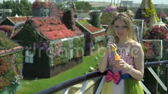 可爱的女孩在花园的阳台上吹着泡泡童话风格做肥皂泡的漂亮女人视频的预览图