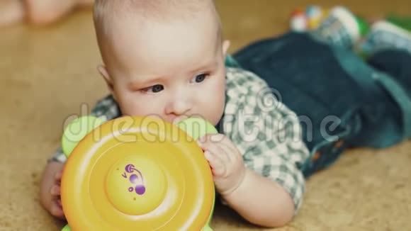 小婴儿有牙齿他咀嚼玩具孩子躺在地板上视频的预览图