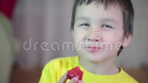 棕色头发的小男孩吃草莓微笑和魅力4K视频的预览图