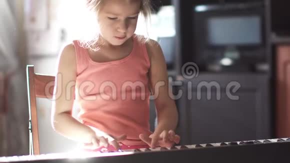 孩子在家弹钢琴这个小女孩正在学习弹电子钢琴阳光下的女孩视频的预览图