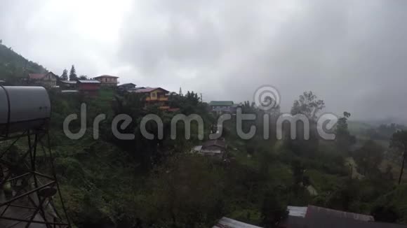 在一个雾蒙蒙的早晨乌云在一个多山的城市的屋顶上移动视频的预览图