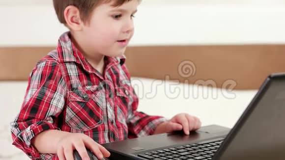 儿童使用笔记本电脑小男孩使用触摸板和无线鼠标玩电脑游戏设备视频的预览图