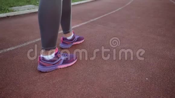 那个女孩沿着跑步机在体育场周围跑步腿部特写后景视频的预览图