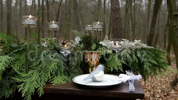 用云杉树枝蜡烛玻璃和盘子装饰的木桌的特写镜头秋林视频的预览图