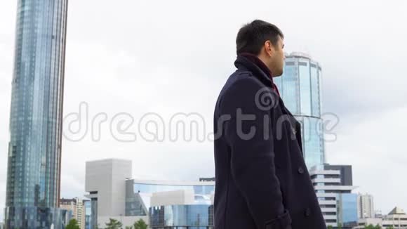 现代多层建筑背景下穿黑色外套的人视频的预览图