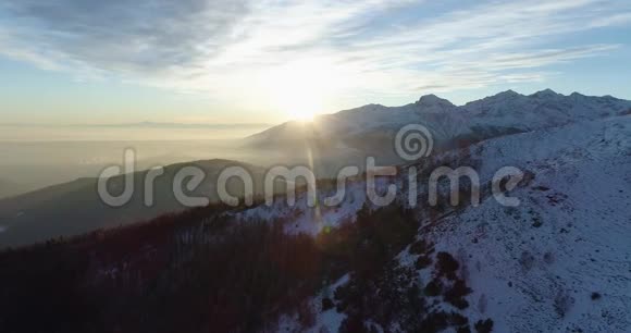 在日落或日出时侧面俯瞰冬季雪山和森林黄昏或黎明的阳光视频的预览图