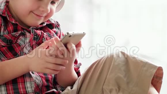 儿童戴耳机儿童玩智能手机通过无线耳机听音乐视频的预览图