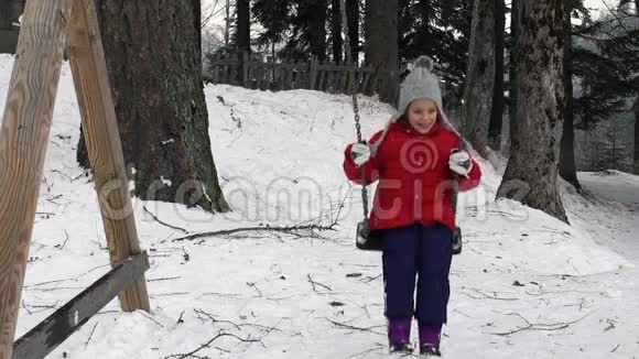 慢动作视频一个小女孩在秋千上摆动而有人向她扔雪球视频的预览图