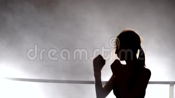 女孩年轻的女人做影子拳击跆拳道烟雾中的轮廓视频的预览图