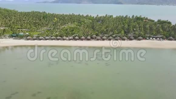海景天堂岛沙滩上有平房海边的绿色热带岛屿上的豪华度假海滩视频的预览图