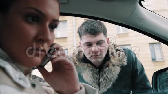 身穿皮夹克的歹徒迫使女人坐在车里打开窗户视频的预览图