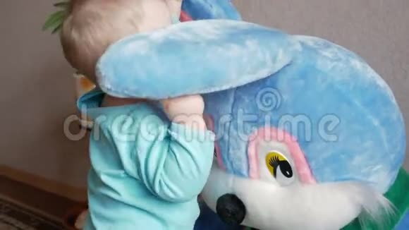 一个2岁的漂亮男孩在家里和一只巨大的毛绒兔子玩耍孩子露眼睛摸耳朵视频的预览图