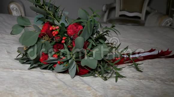 美丽的婚礼花束红玫瑰和牡丹花裹着丝带躺在床上特写镜头视频的预览图