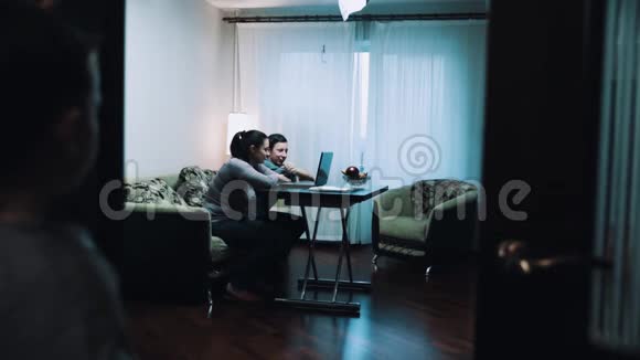 小男孩观察男女在客厅用电脑和爸爸说话视频的预览图