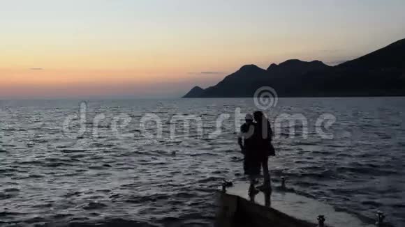男人和女人蹲在码头上看日落视频的预览图