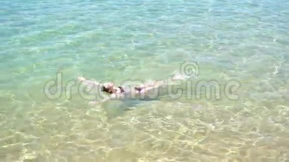 年轻漂亮的女孩躺在蓝色干净的大海里游泳视频的预览图