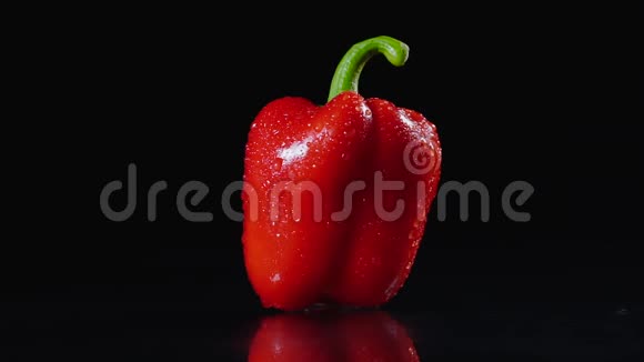 成熟的红辣椒在黑色背景上旋转一滴水在背光中发光特写镜头慢镜头视频的预览图