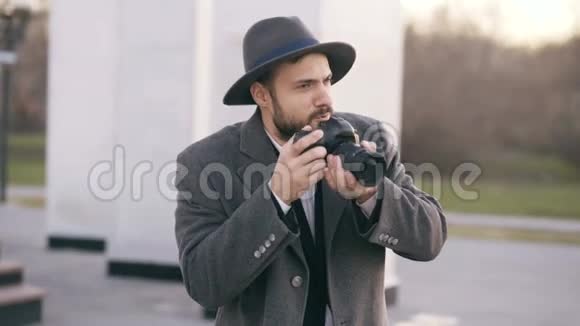 戴着帽子的时尚年轻摄影师站在户外拍摄旅游观光视频的预览图
