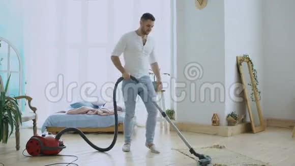 年轻人在用吸尘器打扫房子像吉他手一样跳舞视频的预览图