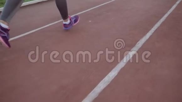 那个女孩沿着跑步机在体育场周围跑步双腿侧视视频的预览图