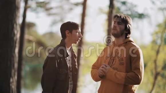 两个男朋友在森林里美丽温暖的夕阳下争吵视频的预览图