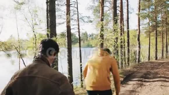 在森林里和朋友散步的时候男人拿起石头扔进湖里视频的预览图