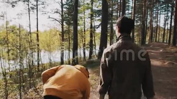 在森林里和朋友散步的时候男人拿起石头扔进湖里视频的预览图