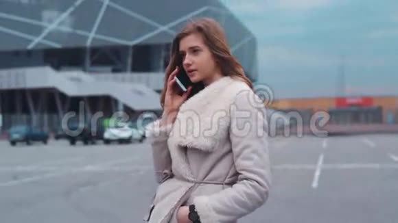 一位年轻漂亮的女士站在一座现代化的商业大厦前在多云的天气里用手机说话的画像视频的预览图