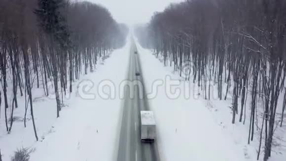 降雪时被冬季森林包围的道路上的交通鸟瞰图视频的预览图