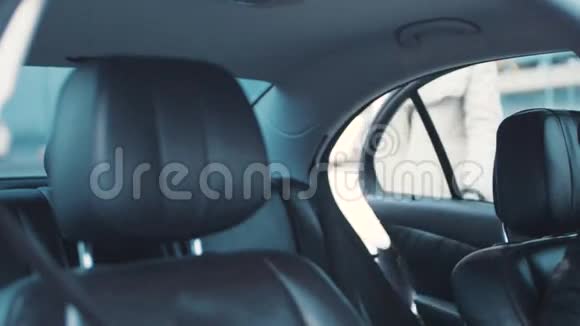 漂亮的金发女郎坐在她的新车上她的手机上里面有现代的真皮座椅和汽车视频的预览图