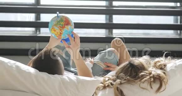 一对恋爱中的情侣在看着环球选择一个蜜月旅行的地方视频的预览图