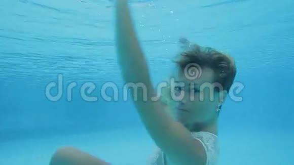 穿着泳装摆姿势游泳在水下旋转的美丽迷人女子视频的预览图