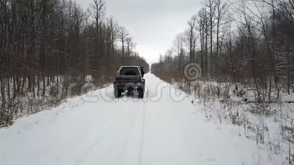 从空中观看越野车6x6在冬天的森林里骑在白雪覆盖的道路上后景视频的预览图