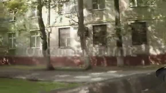 汽车沿着旧砖砌成的公寓楼行驶视频的预览图