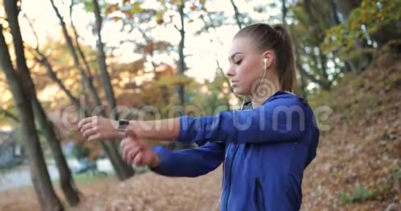 在公园里工作穿着蓝色夹克衫的年轻女子准备用漂亮的衣服伸展手臂和腿视频的预览图