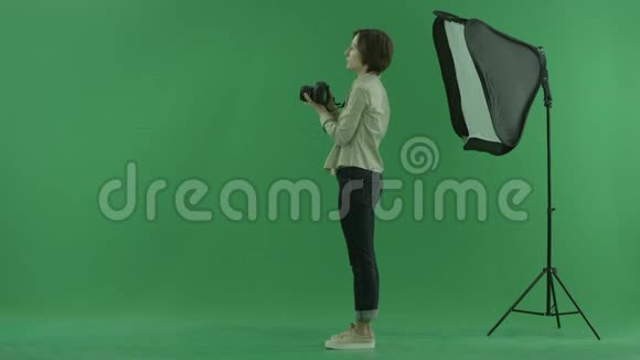 一位年轻女子在绿色屏幕上左手边拍照并纠正站立的模特视频的预览图